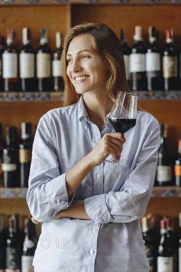 Smiling young woman holding glass of red wine