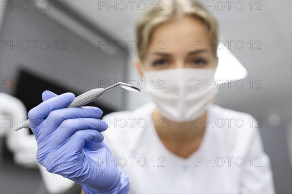 Patient point of view of dental assistant holding dental equipment