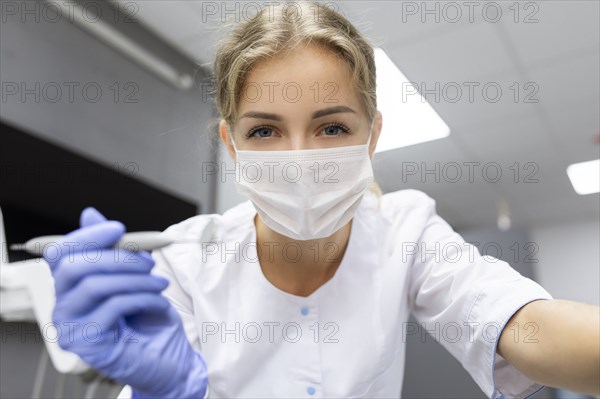 Patient point of view of dental assistant holding dental equipment