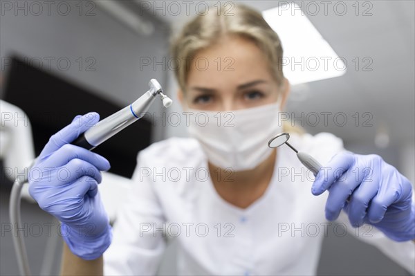 Patient point of view of dental assistant holding dental equipment