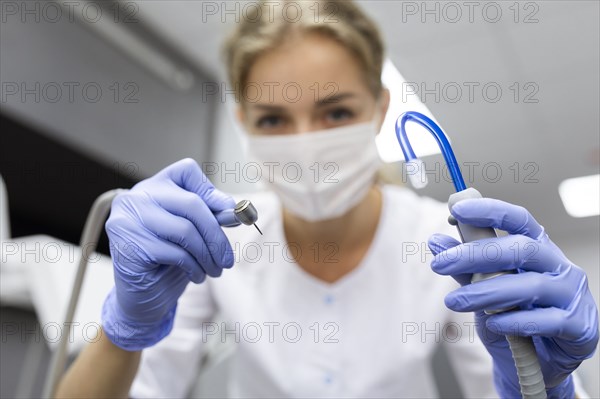 Patient point of view of dental assistant holding dental equipment