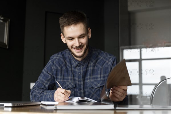 Smiling young businessman writing in note pad