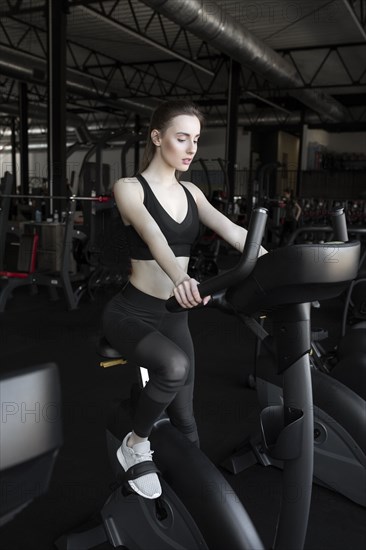 Young woman using exercise bike in gym