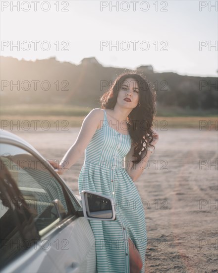 Young woman wearing striped dress by car