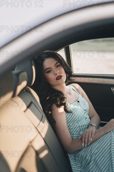 Young woman wearing striped dress sitting in car