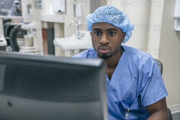 Nurse wearing hair net using computer in hospital