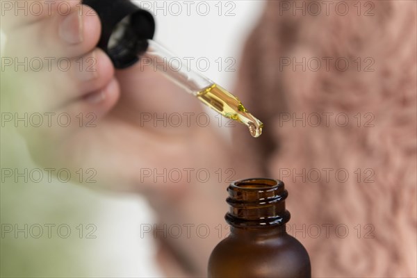 Hand of woman holding pipette of beauty oil