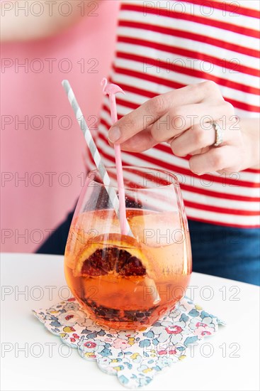 Woman holding flamingo shaped stirrer in cocktail