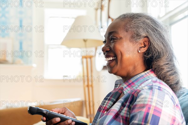 Mature woman with remote control watching television