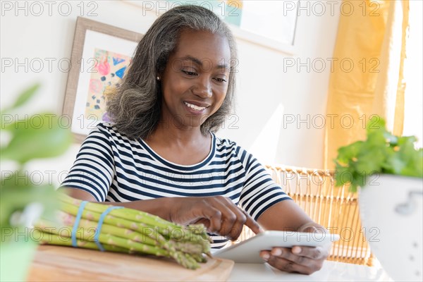 Smiling mature woman looking at digital tablet