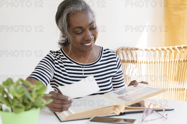 Smiling mature woman looking at scrapbook