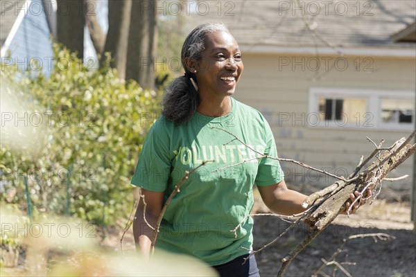 Mature woman volunteer collecting branches in garden