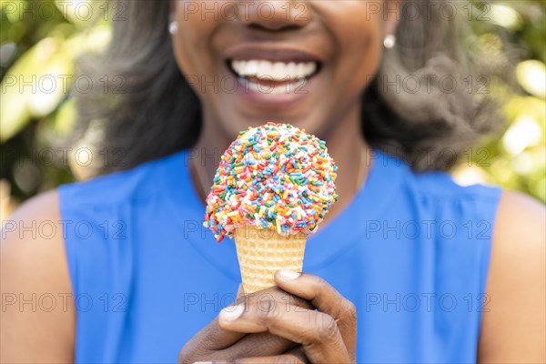 Mature woman holding ice cream cone with sprinkles