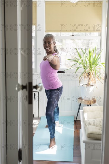 Mature woman doing yoga at home