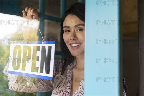 Woman turning open sign in shop window