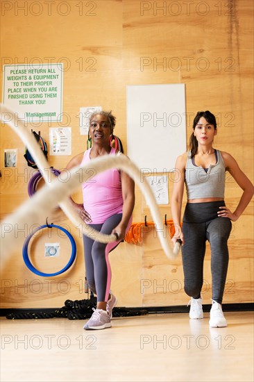 Women exercising with battle ropes in gym