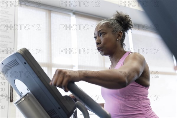 Mature woman exercising on elliptical machine