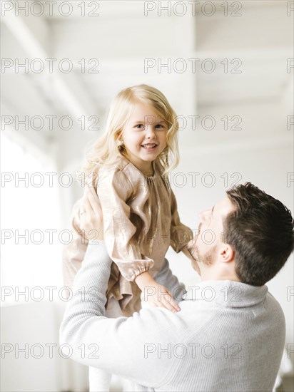 Mid adult man lifting his daughter
