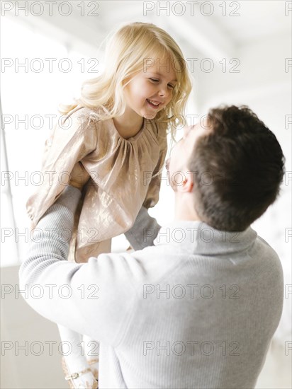 Mid adult man lifting his daughter