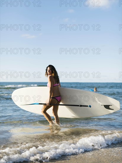 Woman with paddleboard and oar on beach