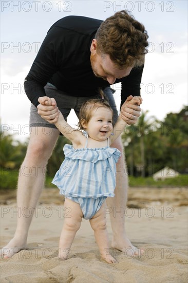 Man playing with baby daughter on beach