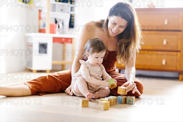 Woman and her baby daughter playing with toy blocks