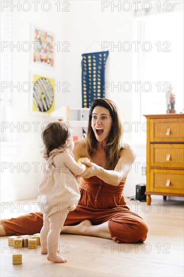 Excited woman holding her baby daughter's hands