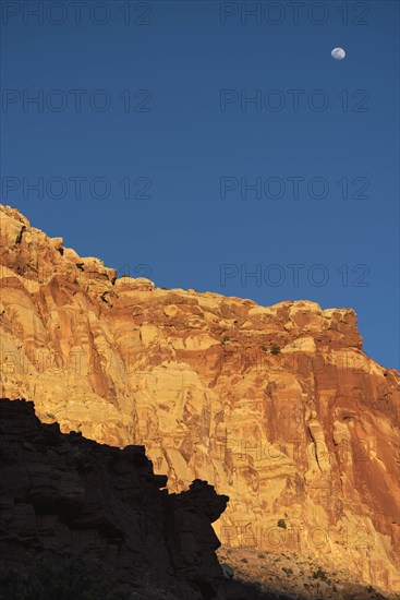 Moon over cliff in shadow in Capitol Reef National Park, USA