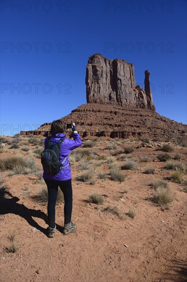 Woman photographing butte in Monument Valley, Arizona, USA