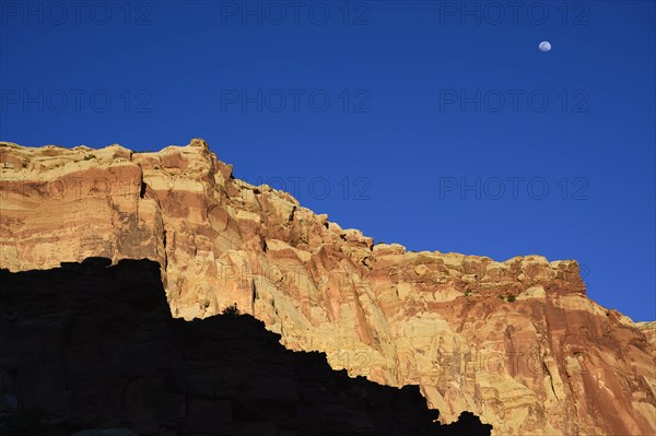 Moon over cliff in shadow in Capitol Reef National Park, USA