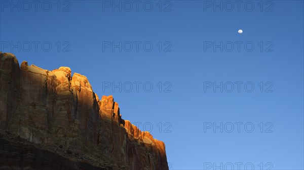 Moon over cliff in shadow in Capitol Reef National Park, USA