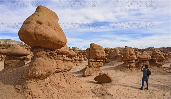 Woman photographing hoodoos in Goblin Valley State Park, Utah, USA