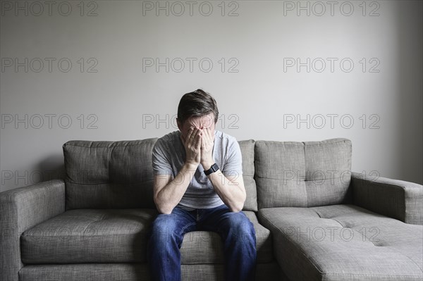 Depressed mature man sitting on couch