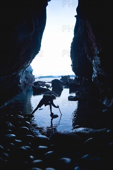 Teenage boy exploring care with rocks in La Jolla, California