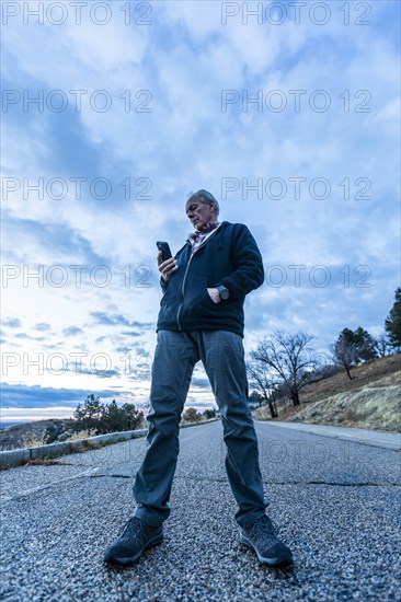 Low angle view of man holding smart phone on road