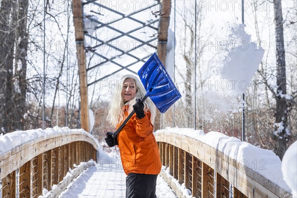 Mature woman shoveling snow off of footbridge