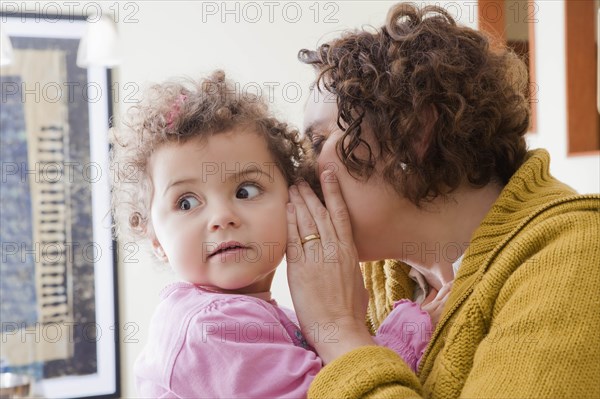 Mother whispering into her daughter's ear