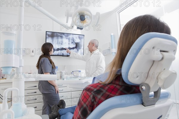 Patient by dentist examining X-ray of teeth