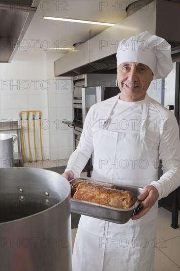 Chef holding meat in roasting tray