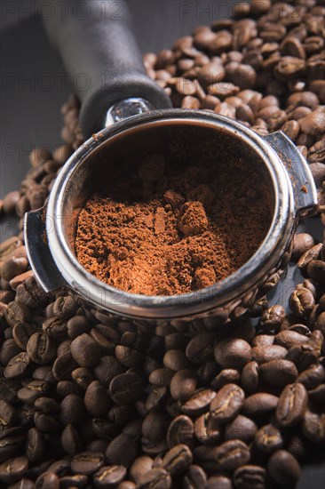 Portafilter holding ground coffee on roasted coffee beans