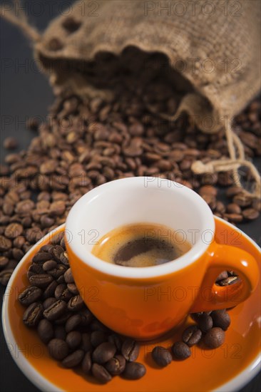 Orange cup of coffee with roasted coffee beans