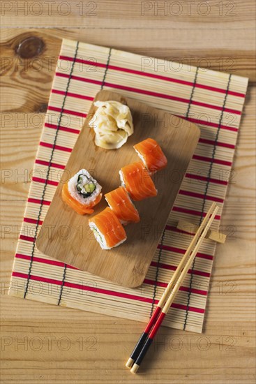 Salmon sushi on cutting board with chopsticks and mat