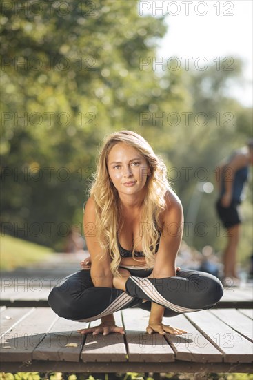 Young woman practicing yoga on boardwalk