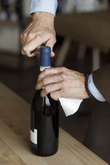 Hands of man opening bottle of wine