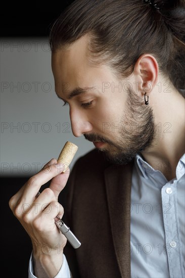 Young man smelling wine on cork at tasting