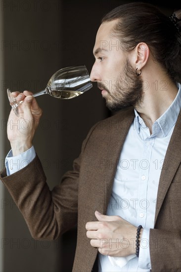 Young man smelling wine in glass at tasting