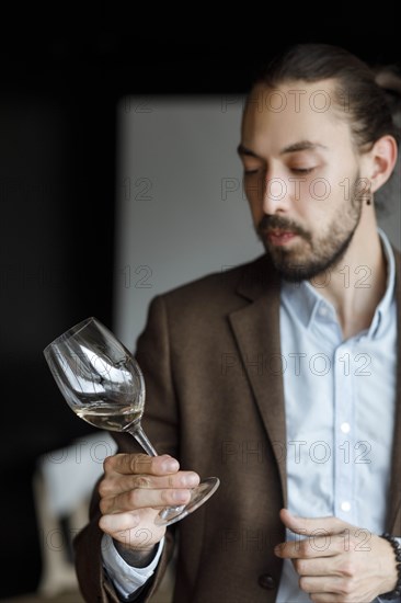 Young man examining glass of wine