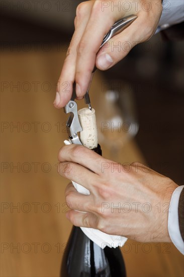 Hands of man opening bottle of wine