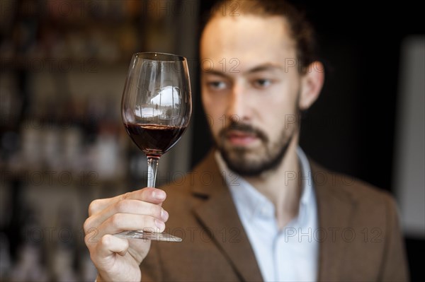 Young man examining glass of wine