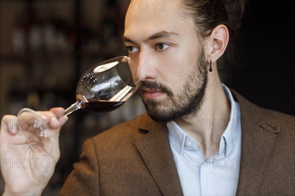 Young man smelling wine in glass at tasting